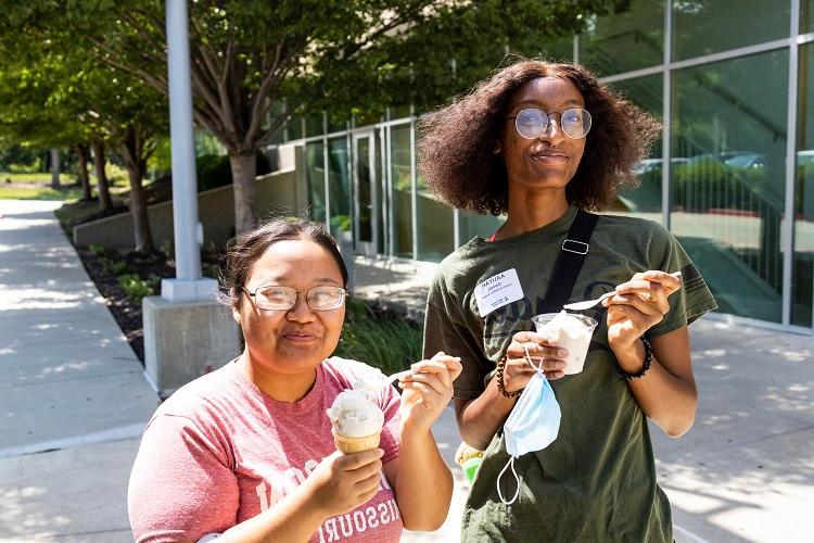 阿莉娅·丹尼尔斯(右边)和她的朋友在外面吃冰淇淋时对着镜头微笑